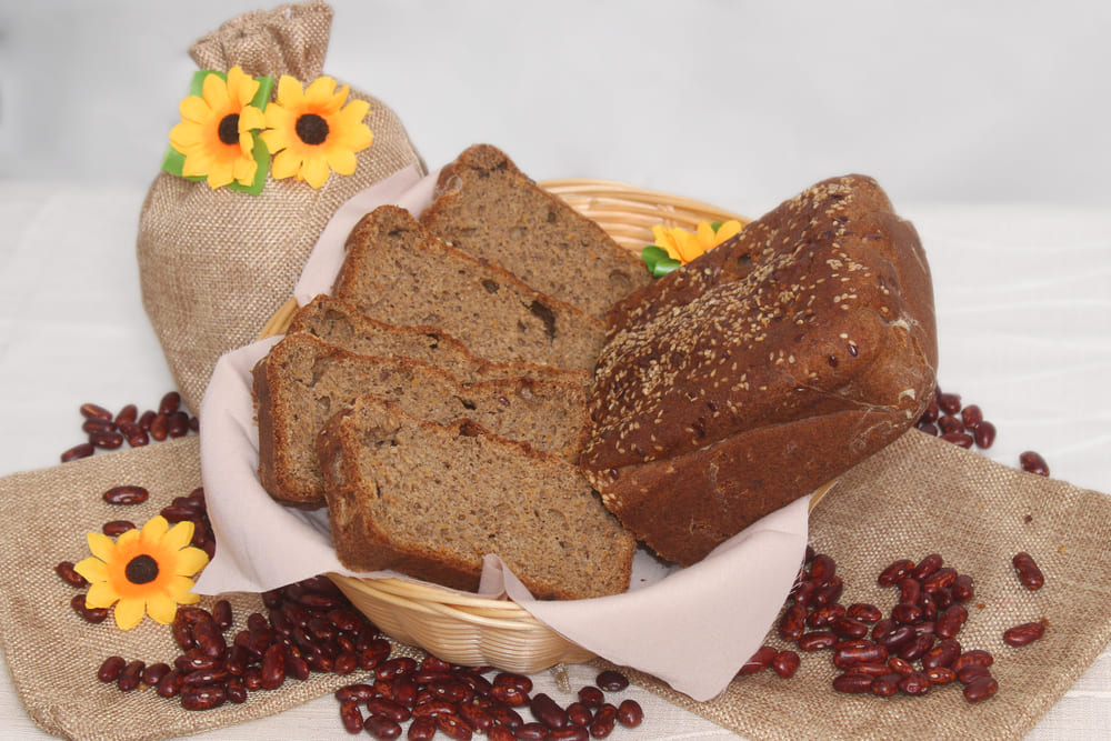 Imagen de pan de legumbres dentro de una canasta. Alrededor, bolsitas de tela y decoración floral.